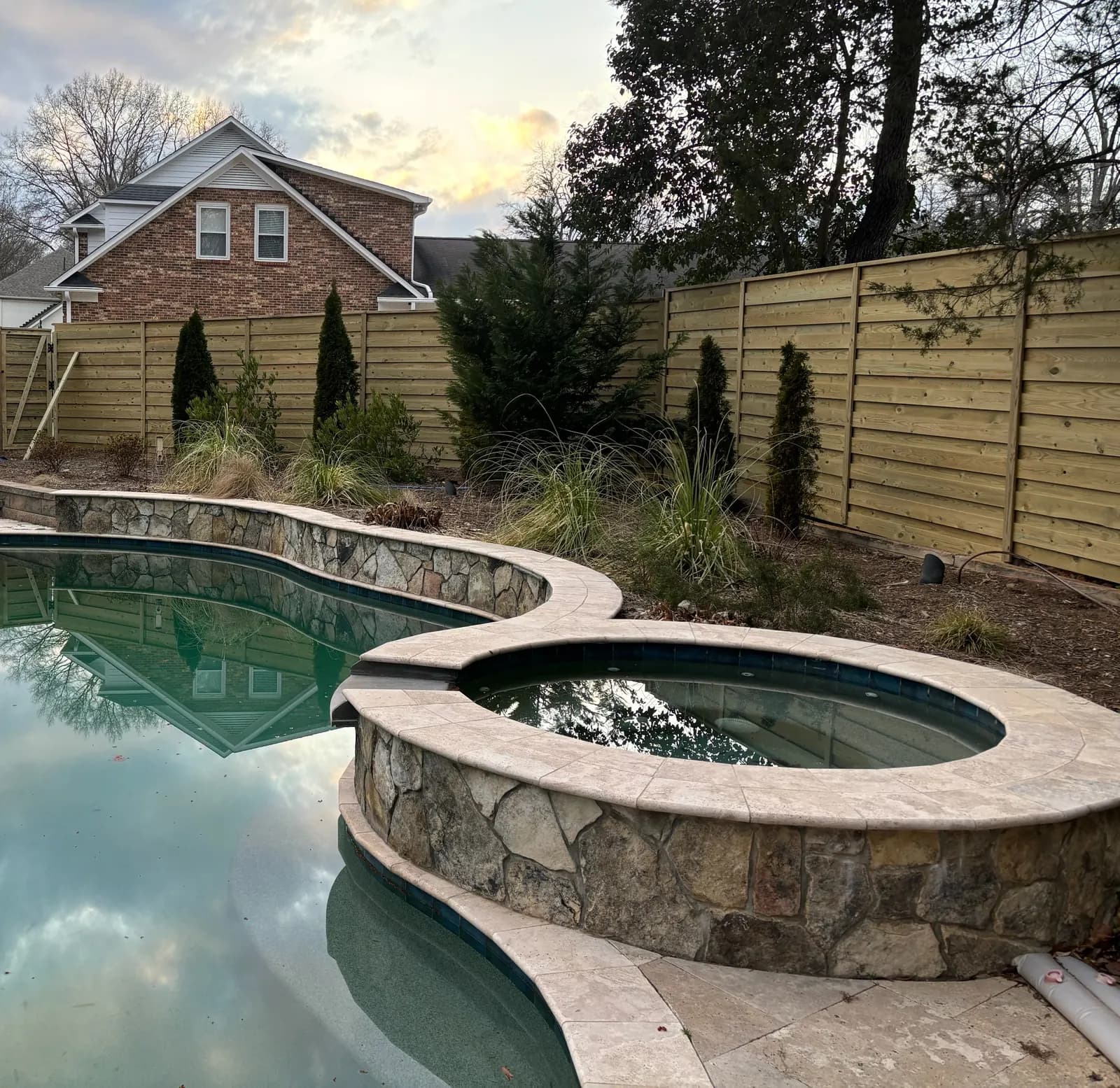 Horizontal wood privacy fence around a backyard pool and spa.