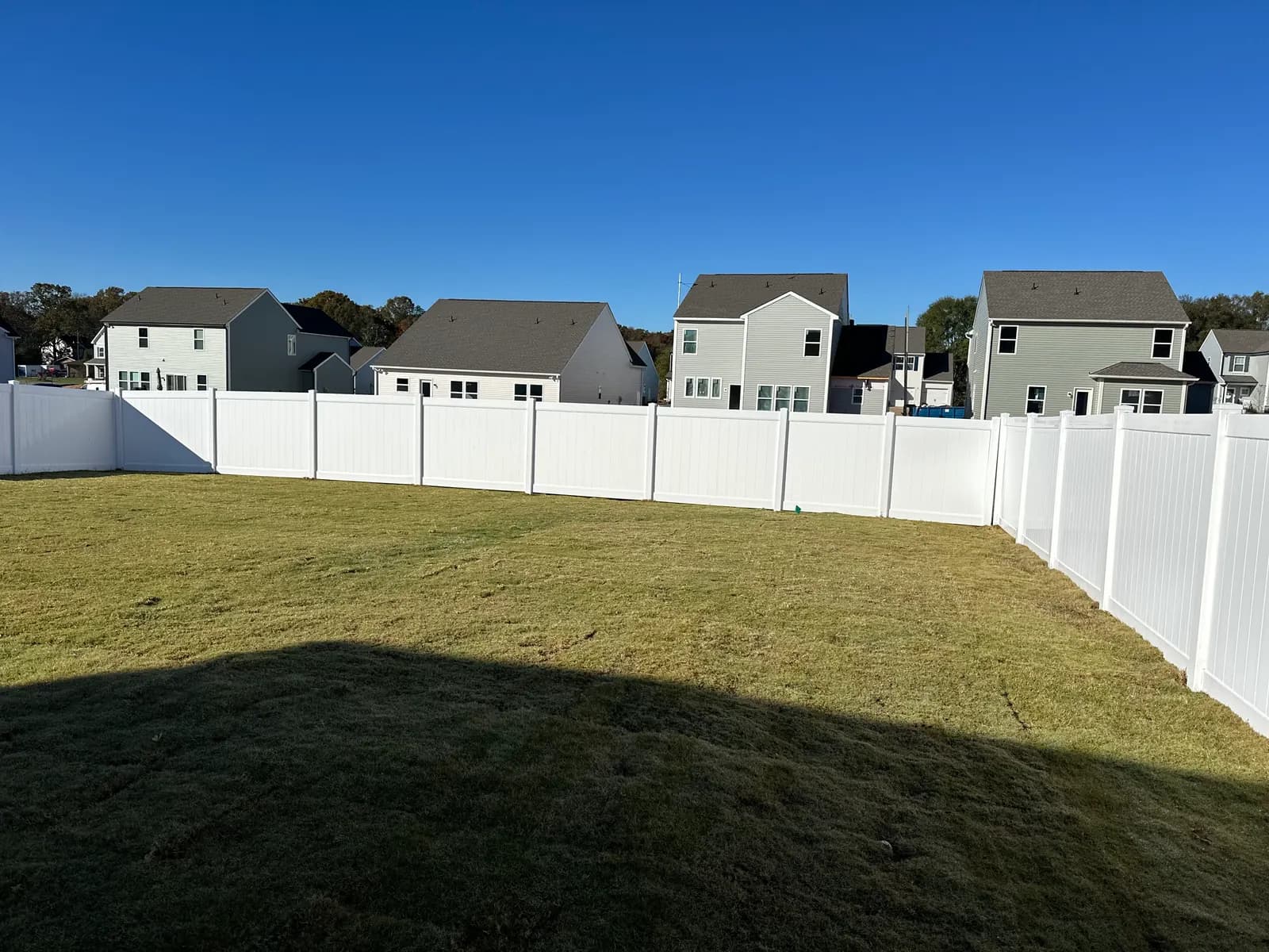 White vinyl privacy fence enclosing a backyard lawn.