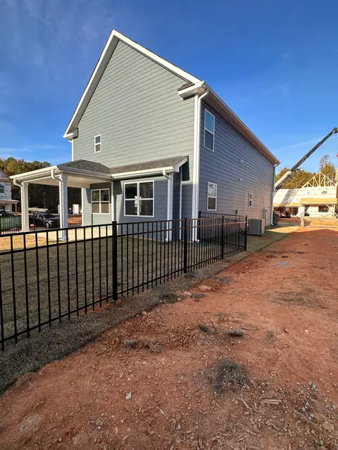 Black aluminum fence enclosing the backyard of a newly built gray house.