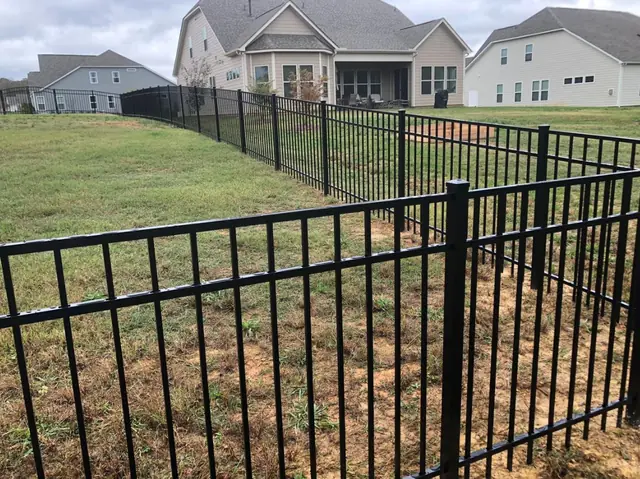Black aluminum fence with three rails enclosing a large grass yard.