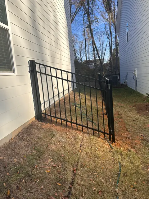 Black aluminum walk gate between two houses.