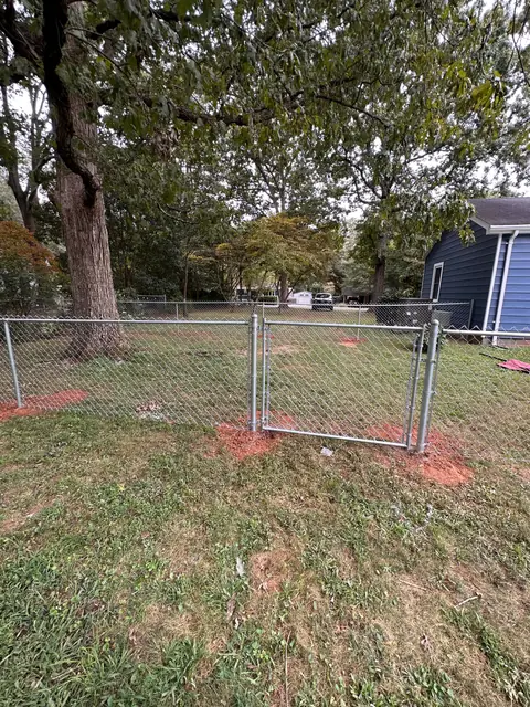 Galvanized chain link fence with a double gate in a backyard.