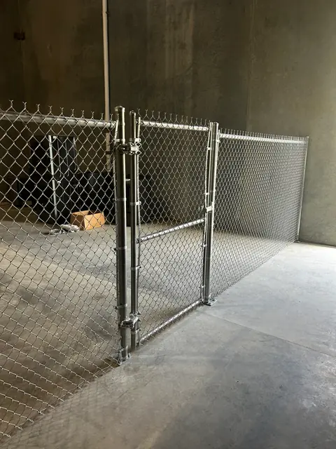 Chain link gate set in a chain link partition inside a concrete building.