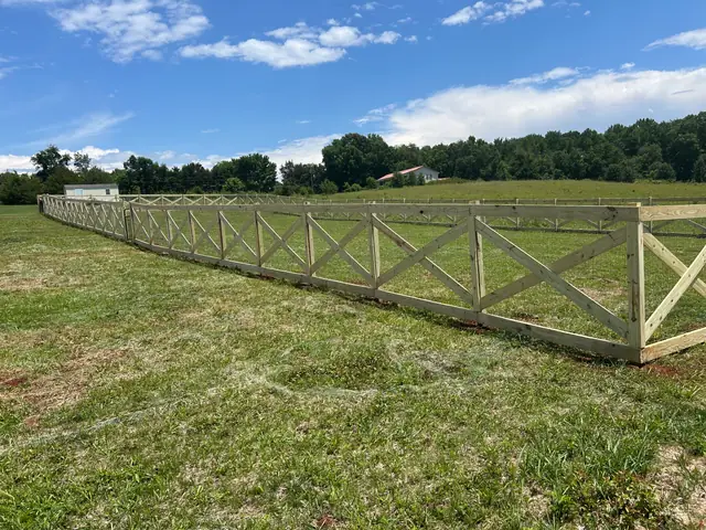 Long line of wood crossbuck fence across a field.