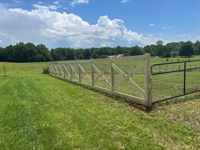 Wood crossbuck fence with a metal farm gate in a pasture.