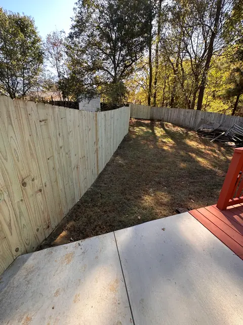 Dog-ear wood privacy fence enclosing a backyard beside a concrete patio.