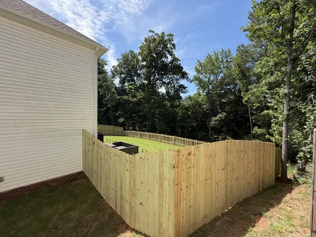 Dog-ear wood privacy fence running from the corner of a house.