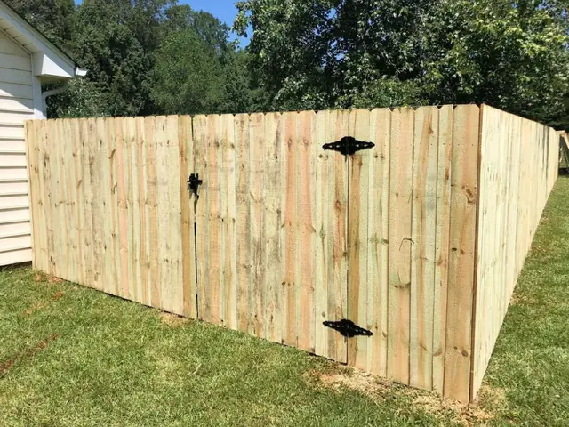 Dog-ear wood privacy fence with a gate and black hardware.