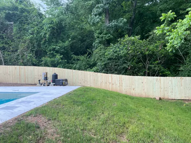 Dog-ear wood privacy fence behind a pool deck.