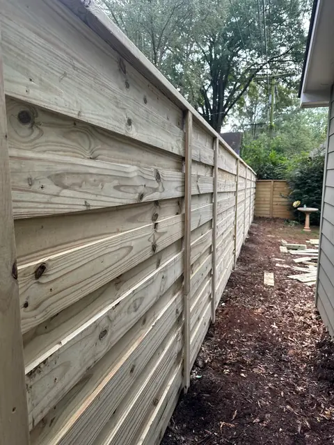Horizontal board-on-board wood fence along a side yard.