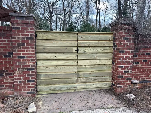 Horizontal board wood double gate between brick columns.