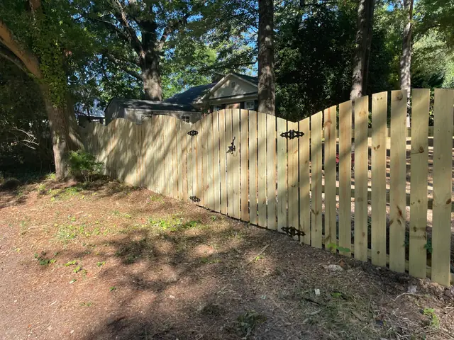 Wood semi-privacy fence with an arched top and a gate with black hardware.