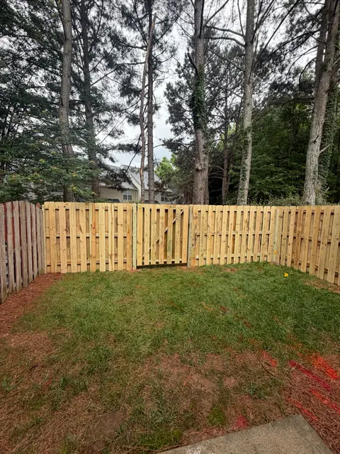 Shadowbox wood fence with a gate across the back of a yard.