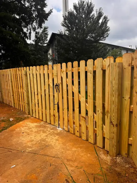Dog-ear shadowbox wood fence with a gate and black latch.