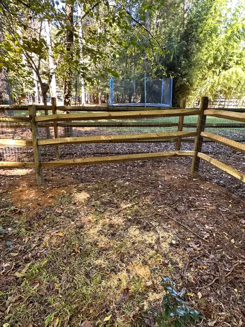 Split rail fence corner with welded wire in a backyard.