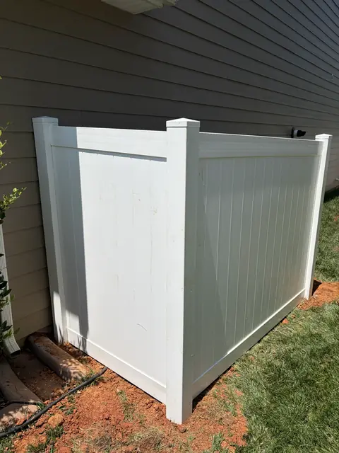 Small white vinyl privacy enclosure against the side of a house.