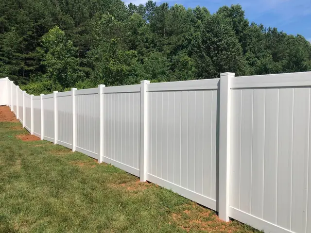 Long run of white vinyl privacy fence along a lawn.