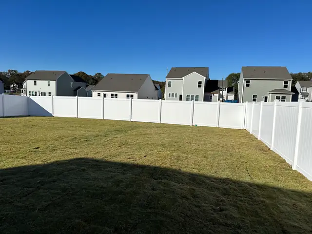 White vinyl privacy fence enclosing a backyard lawn.