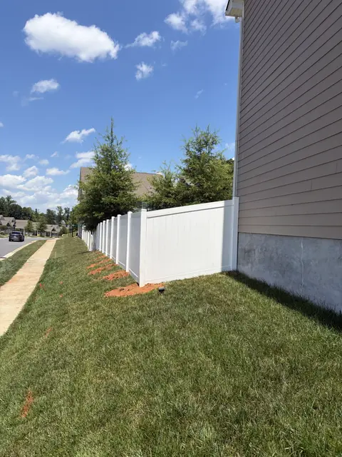 White vinyl privacy fence running beside a sidewalk.