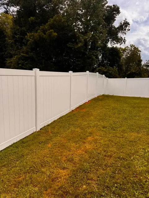 White vinyl privacy fence along a backyard lawn.