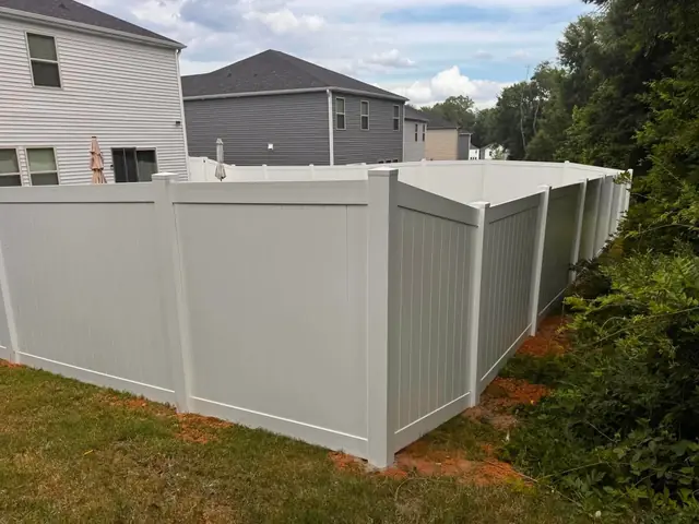 White vinyl privacy fence corner behind two-story homes.