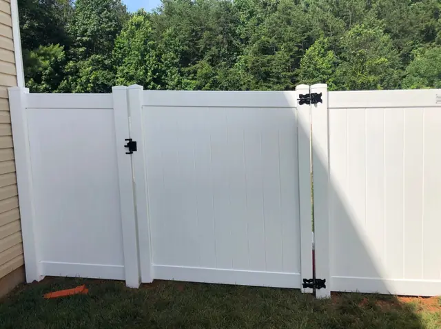 White vinyl privacy fence with a gate and black hardware.