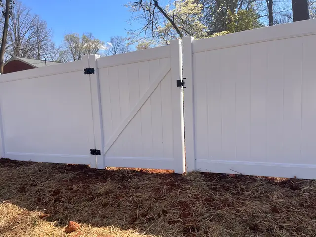 White vinyl privacy fence with a gate.