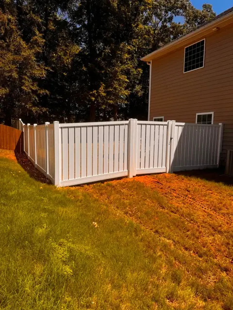 White vinyl semi-privacy fence with spaced pickets beside a house.