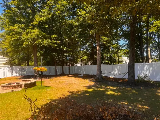 White vinyl fence with spaced pickets around a backyard with a fire pit.