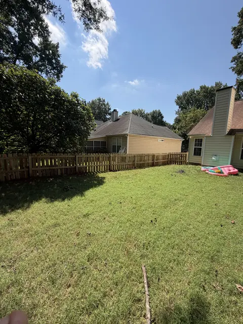 Low wood picket fence around a backyard lawn.