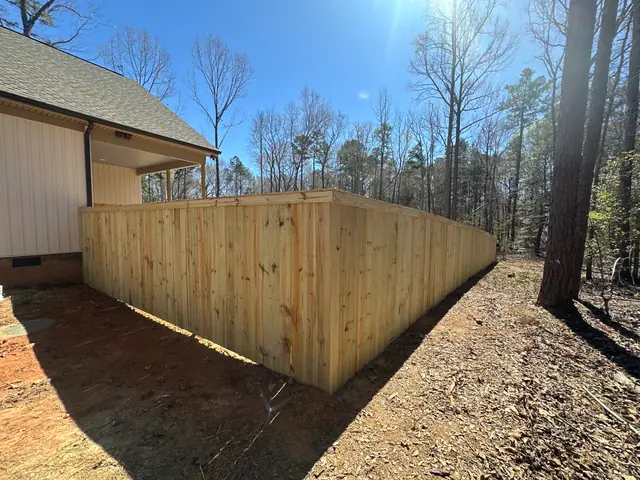 Wood privacy fence with cap and trim around a backyard.