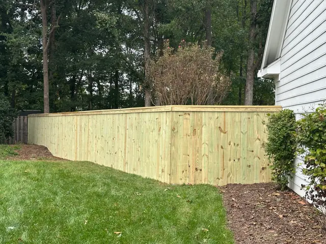 Wood privacy fence with cap and trim beside a white house.