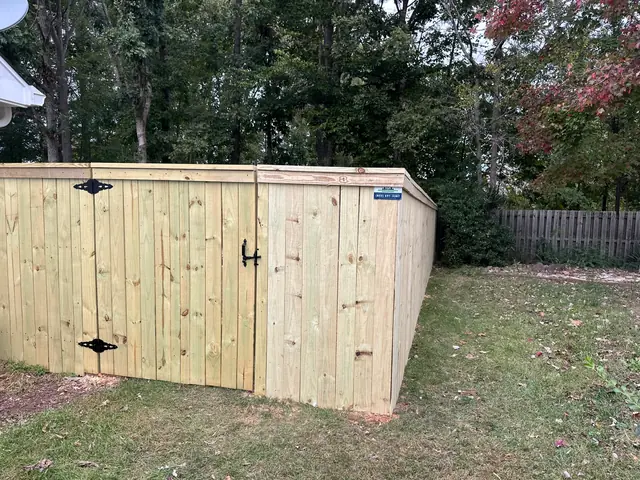 Wood privacy fence with cap and trim and a gate with black hardware.