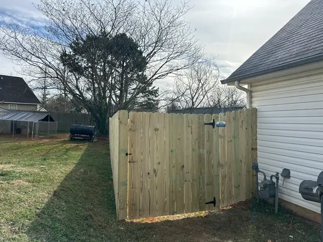 Wood privacy fence and gate at the corner of a house.