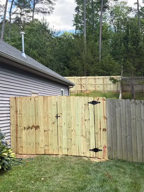 Wood privacy gate with black decorative hinges.